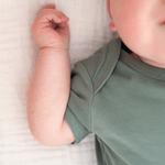 Detail shot of baby arm and sleeve seam of sage green organic cotton short sleeve bodysuit