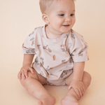 Baby wearing Summer Vibes print bubble romper, looking to the side and smiling in a neutral studio setting