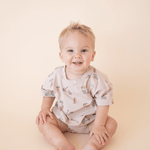 Toddler smiling while wearing bug + bean Summer Vibes bubble romper with short sleeves and organic cotton fabric