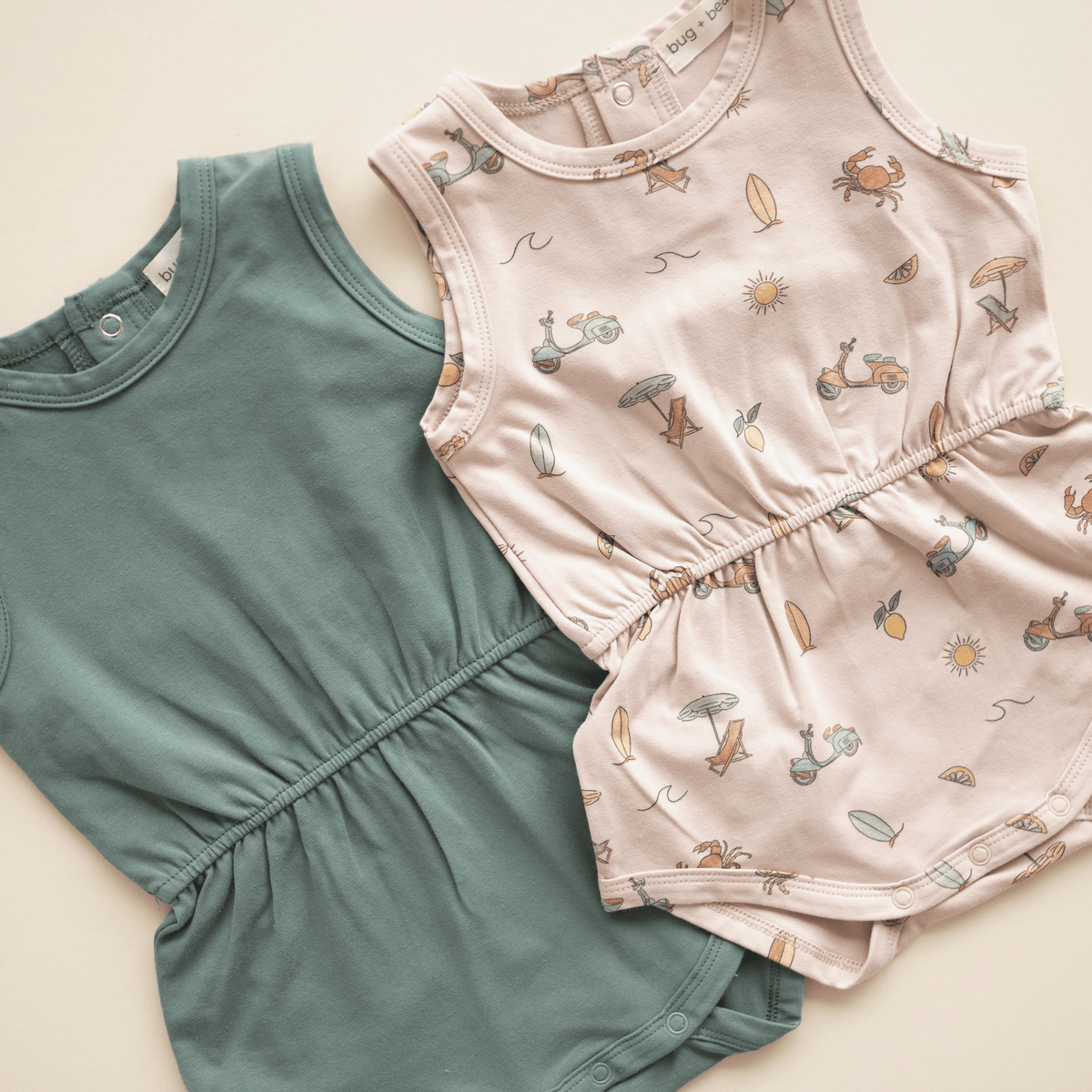 Flat lay of Basil green and Summer Vibes baby rompers.