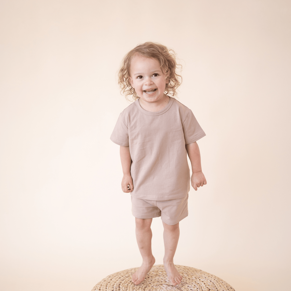 Smiling toddler wearing bug + bean kids mocha short set made from soft organic cotton, perfect for lounging or daytime adventures.