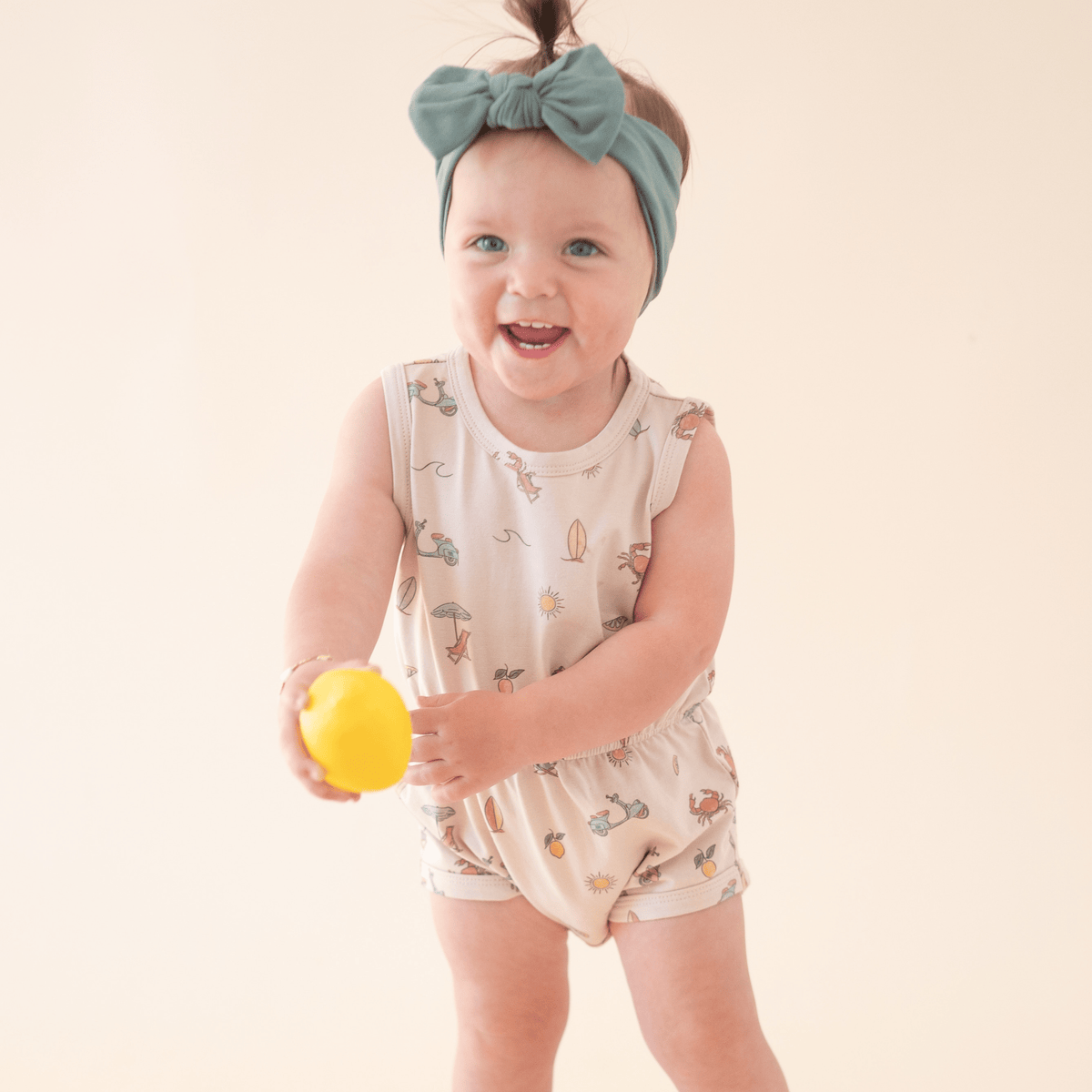 Baby girl in Summer Vibes romper holding lemon.